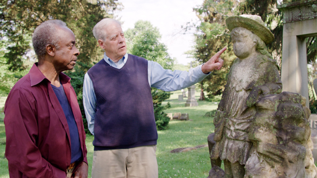 Public TV Series: World's Greatest Cemeteries. Episode 105. Cincinnati, OH. Spring Grove Cemetery & Arboretum. (left to right) Host/Producer Roberto Mighty; Docent Dale Hoyt at the grave of "Chunkie" Singleton, a little girl who perished from Scarlet Fever. ©2021 Roberto Mighty. Photo by Tim Ouillette